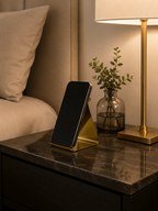 Smartphone on a stand on a nightstand next to a lamp and plant