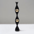 Decorative black and gold sculpture on a white surface with a grey background