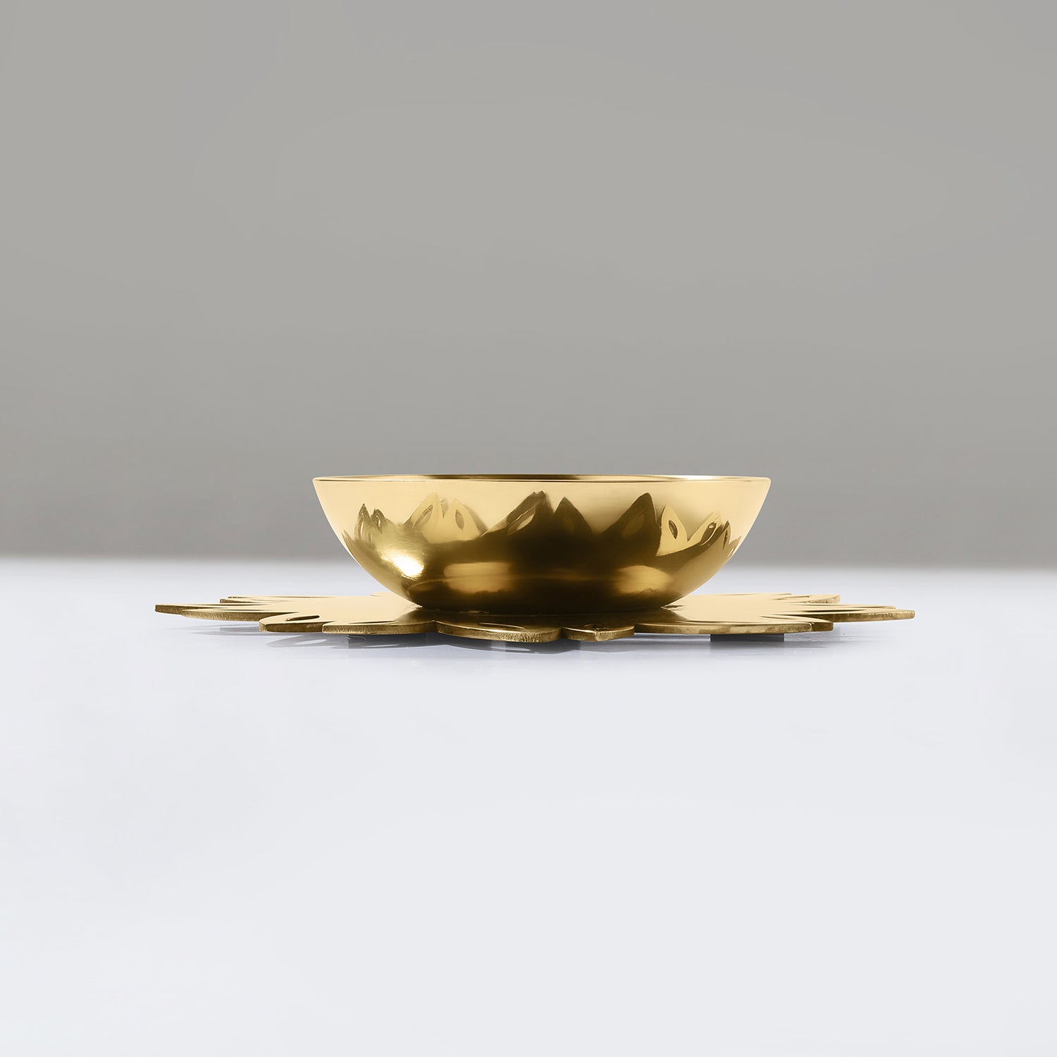 Gold decorative item on a white surface with a gray background