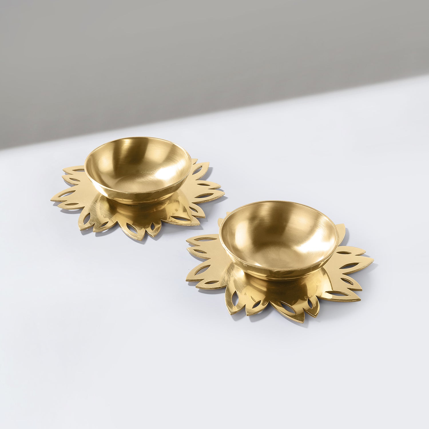 Two gold decorative items with floral designs on a white surface.
