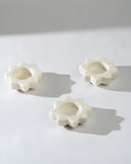 Three  candle holders shaped like flowers on a light grey background