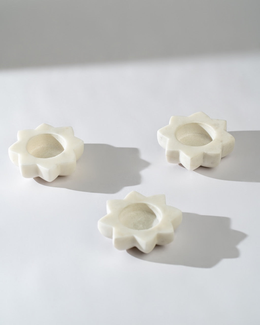 Three  candle holders shaped like flowers on a light grey background