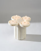 Marble candle holder with four lit candles on a neutral background