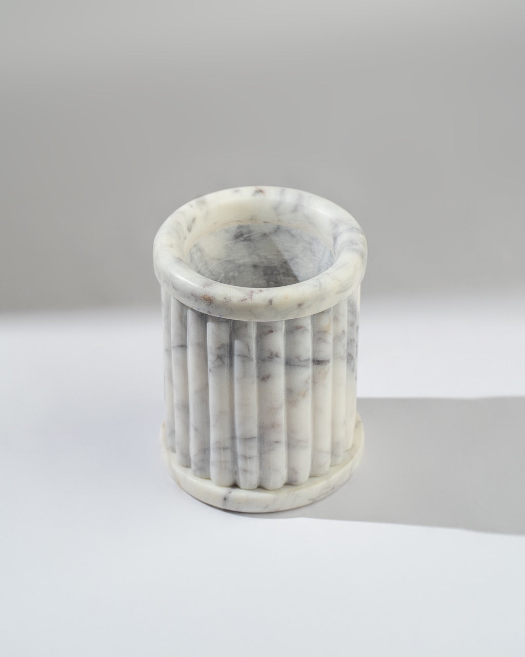 Marble-textured cylindrical container on a light gray background