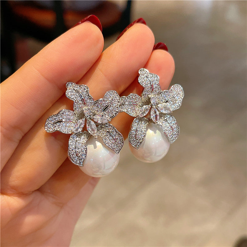 Floral earrings with pearls held in a hand