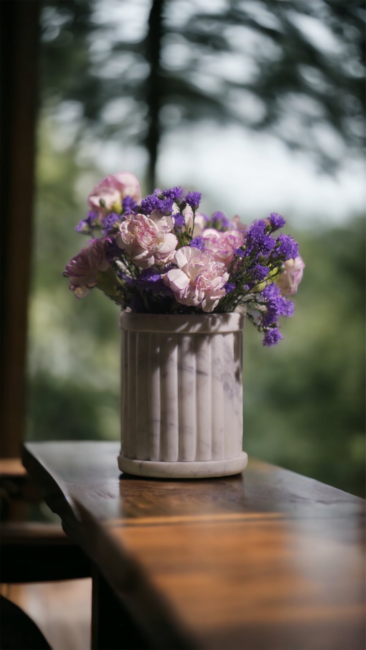 Vase with pink and purple flowers on a wooden table 