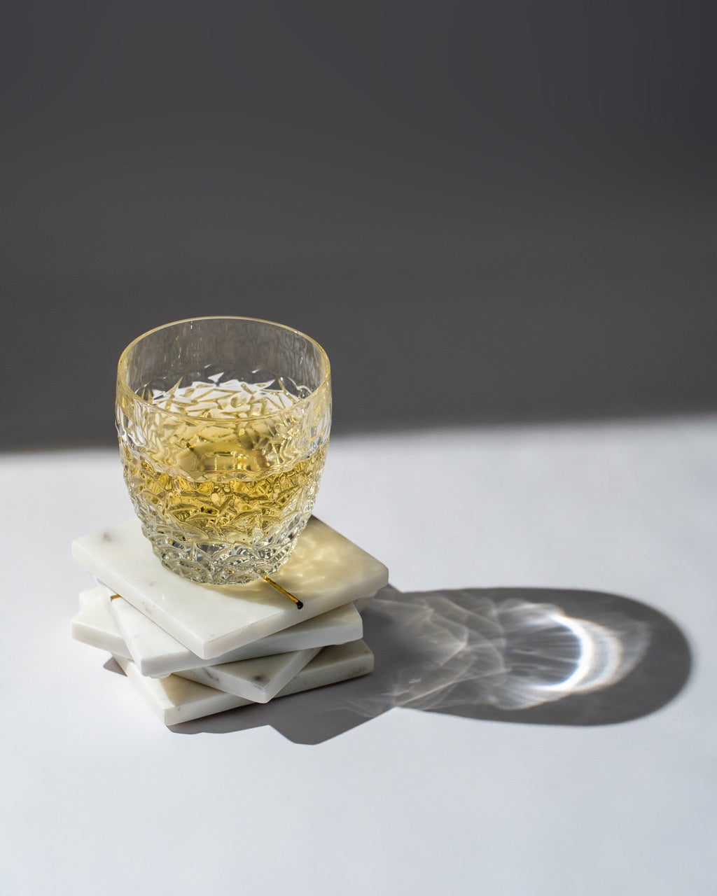 Glass of whiskey on a marble coaster with a dark background