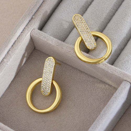 Gold earrings with diamond accents on a gray jewelry box