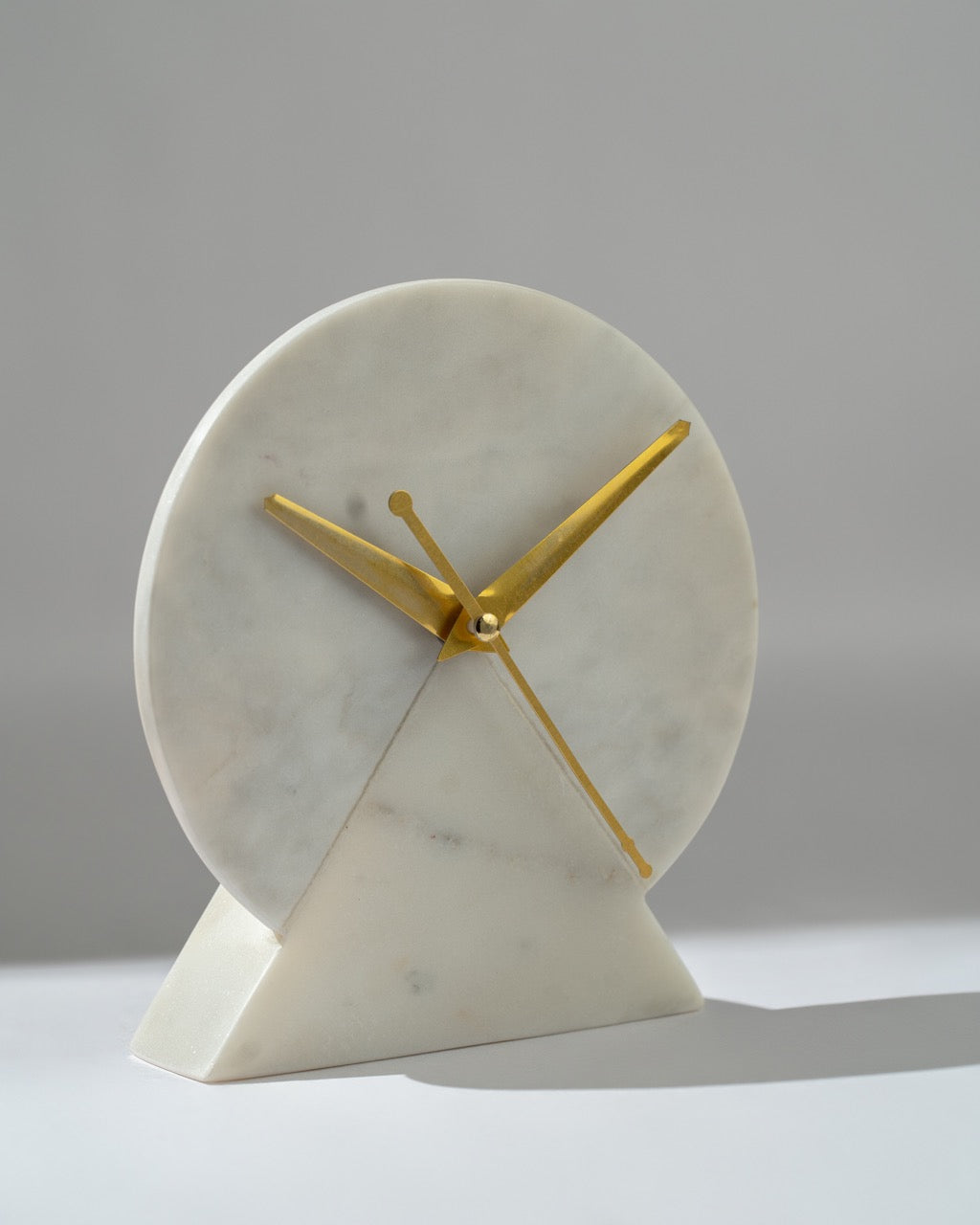 Marble clock with gold hands on a gray background