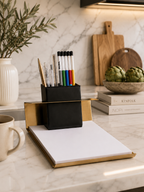 Desk setup with a notebook, pen holder, and coffee mug on a marble surface.
