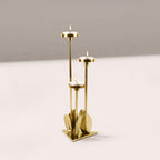 Gold candle holder with three candles on a light gray background