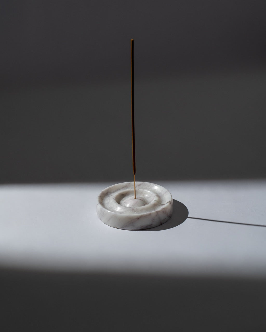 Incense stick on a marble holder against a dark background
