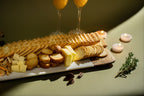 Platter of assorted snacks including crackers, bread, and cheese on a table with candles and glasses in the background.