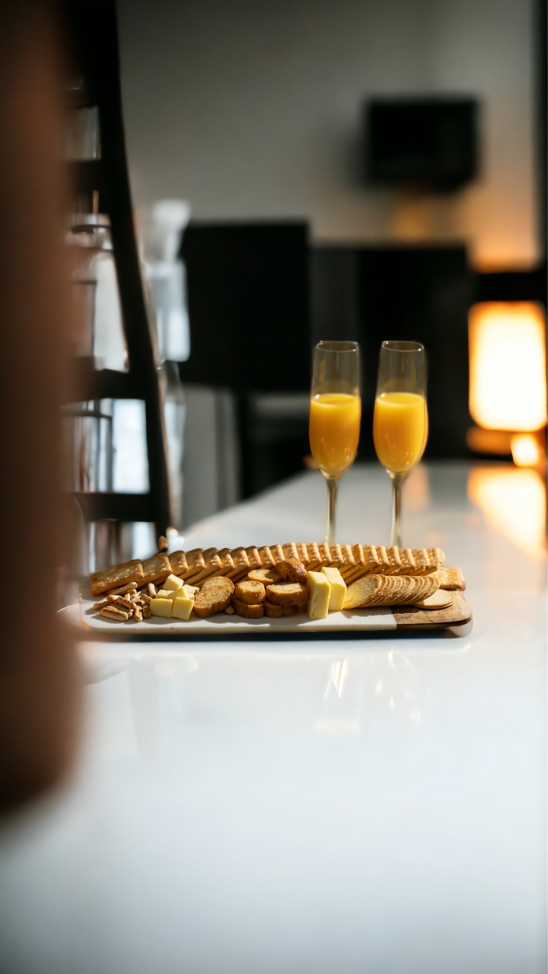 Two champagne flutes with orange juice on a table with waffles and other pastries.
