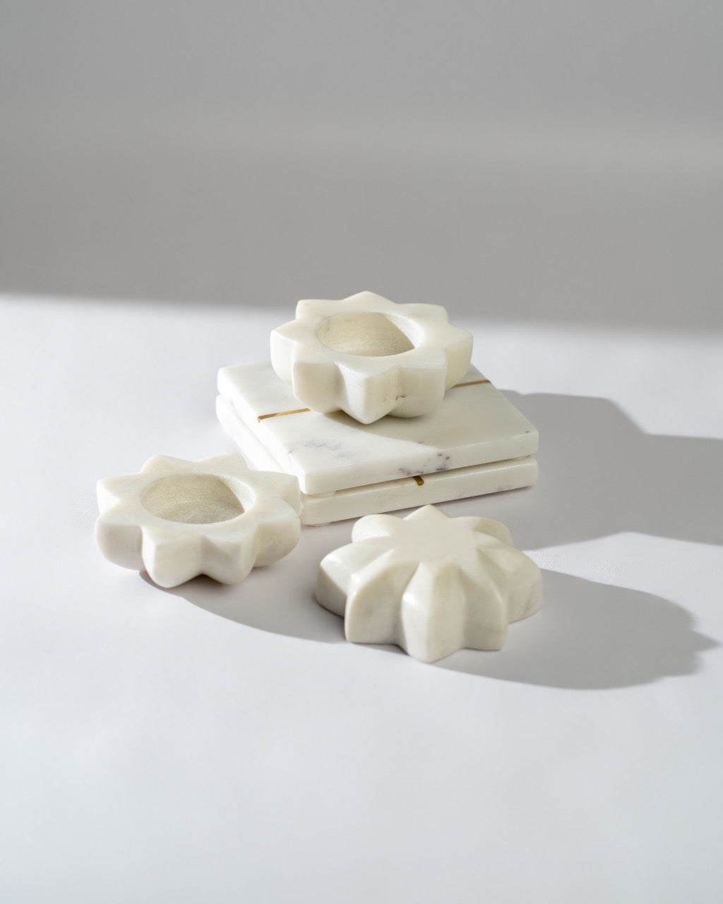 White marble flower-shaped tea lights on a light grey background