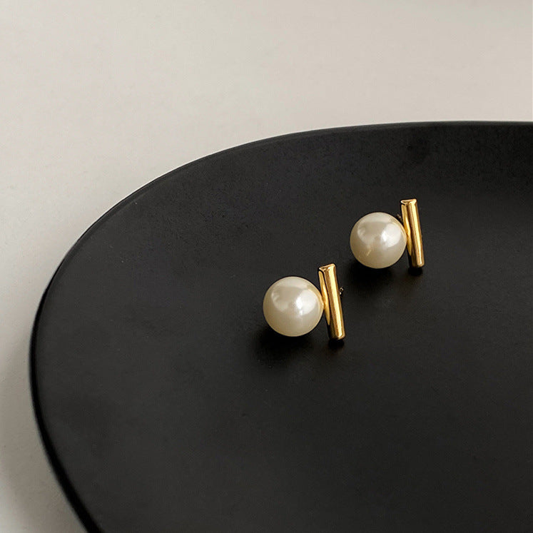 Pearl earrings with gold posts on a black surface
