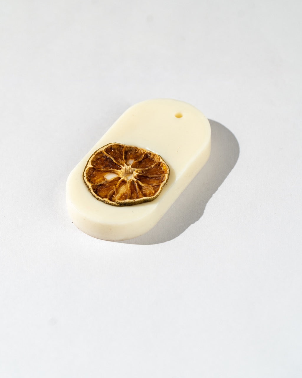 White wax bar with a dried lemon slice on a light grey background