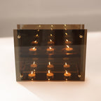 Clear glass display case with lit candles on a white background