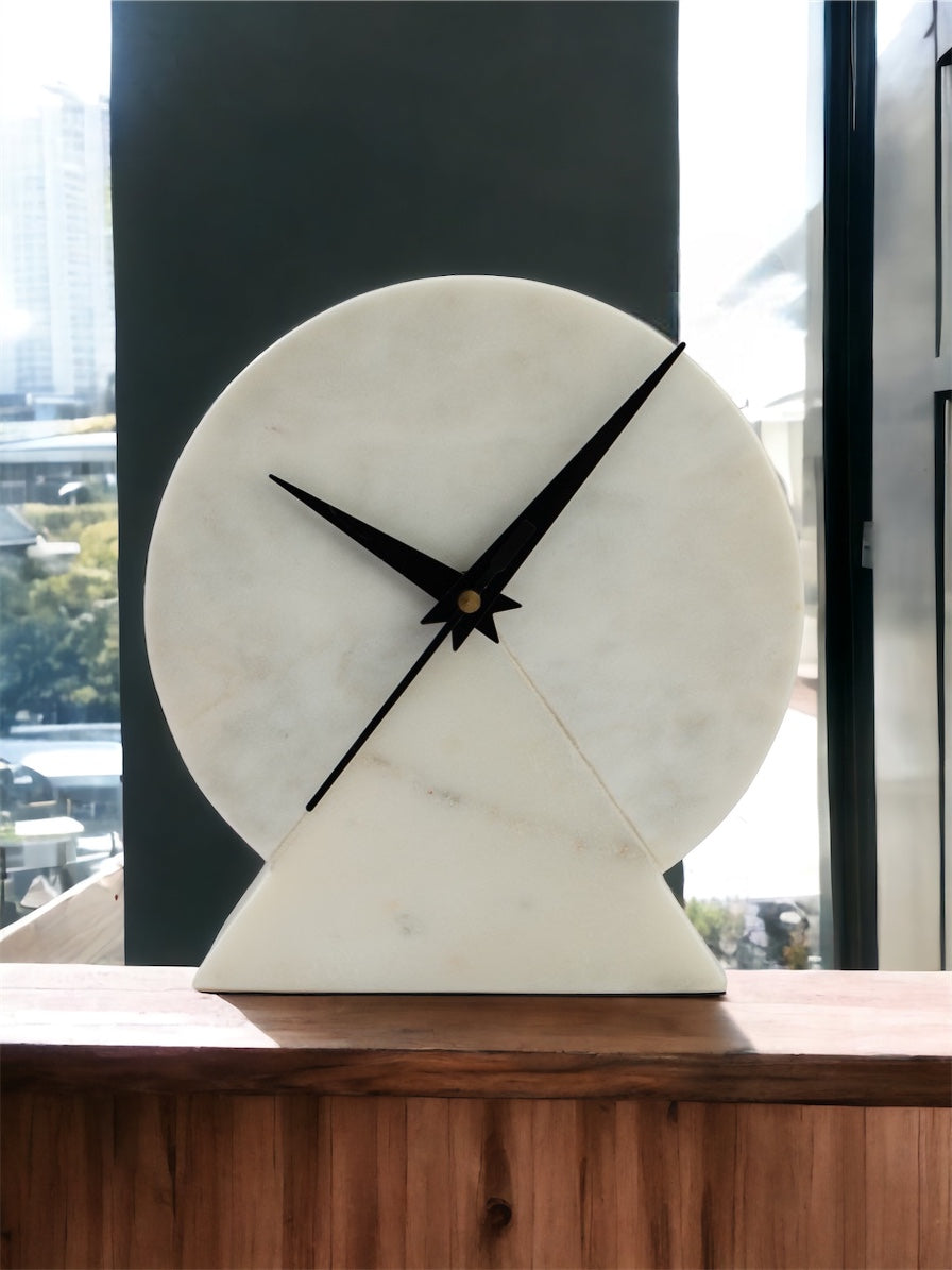 Marble clock on a wooden surface with a blurred window background