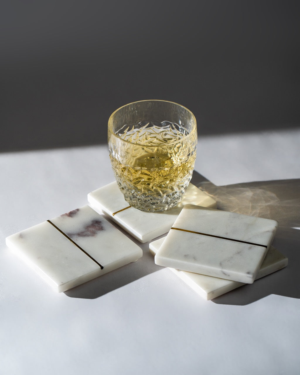 Glass of whiskey on marble coasters with a dark background