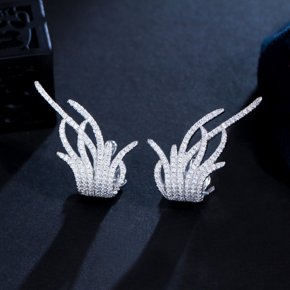 Silver leaf-shaped earrings on a dark textured surface