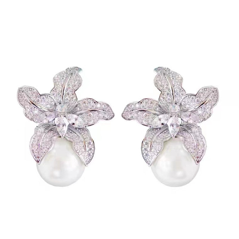 Pair of earrings with floral designs and pearls .