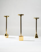 Three gold candle holders of varying heights on a white background