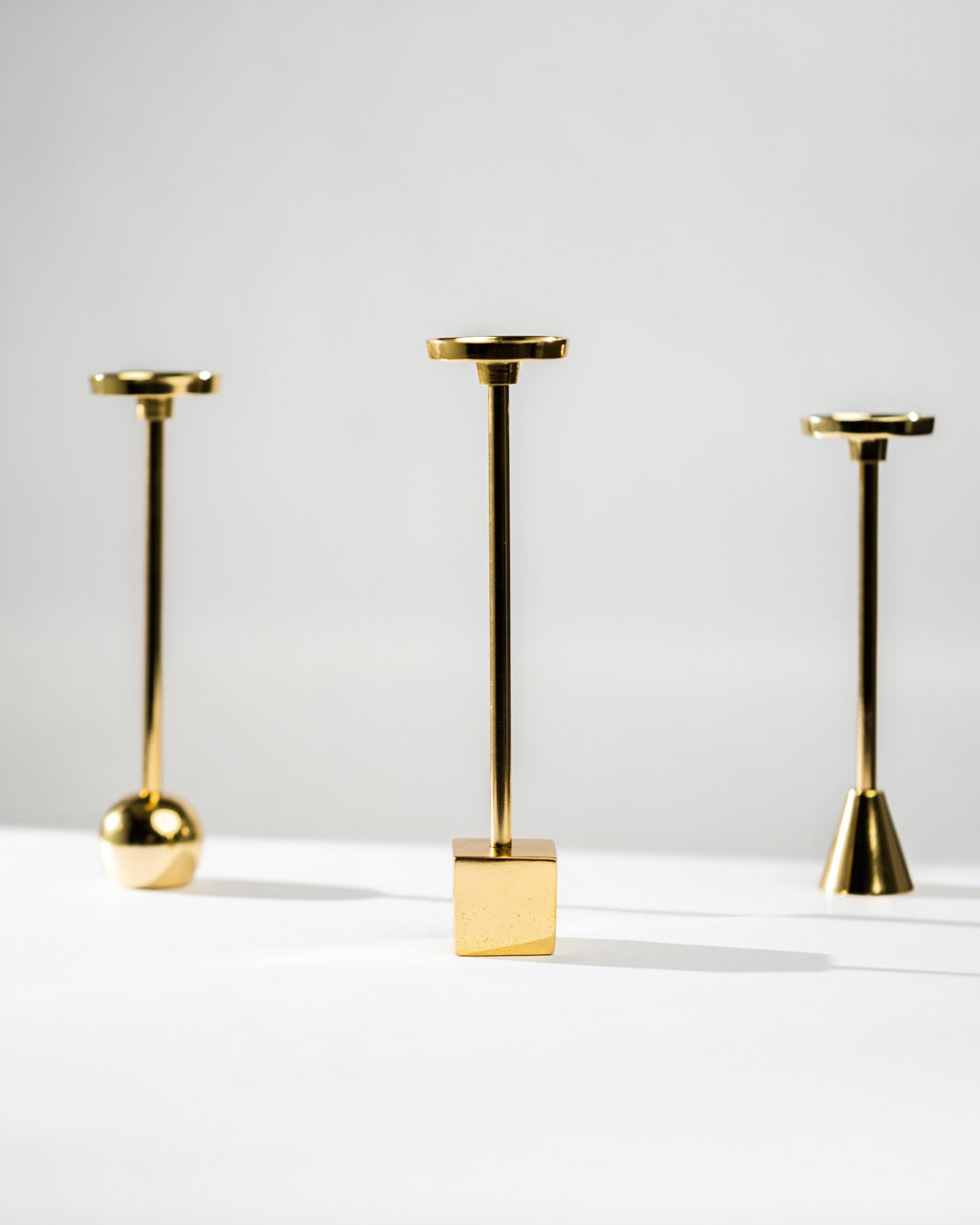 Three gold candle holders of varying heights on a white background