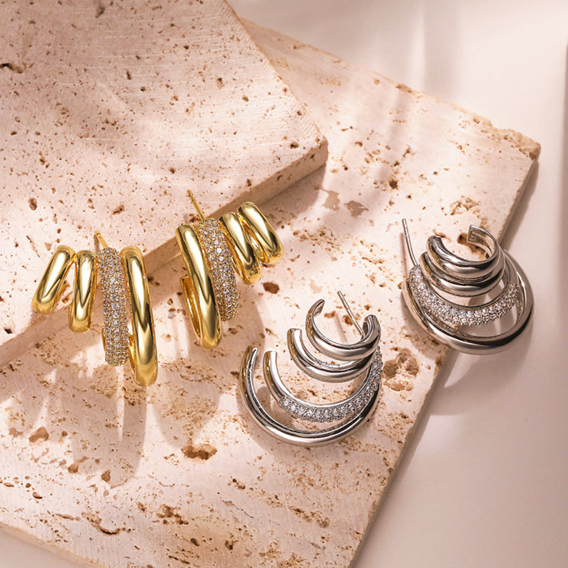 Gold and silver hoop earrings on a textured surface
