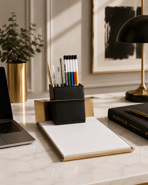 Modern office desk setup with laptop, notebook, and stationery on a marble surface.